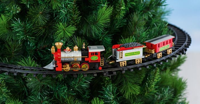 a toy train is on the tracks near a christmas tree