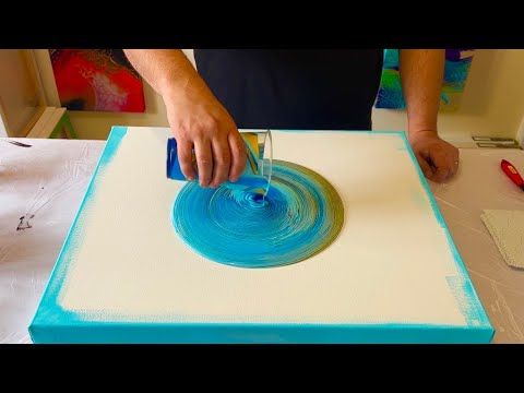 a man is making an art project with blue and white paper on top of a table