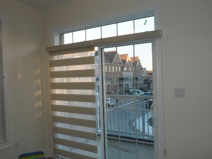 an empty room with sliding glass doors leading to a parking lot in front of the window