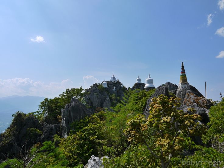 the top of a mountain with many spires on it's sides, surrounded by greenery