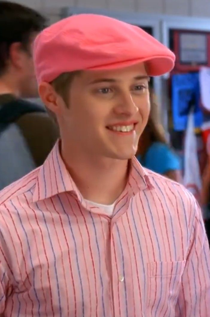 a young man wearing a pink hat and smiling