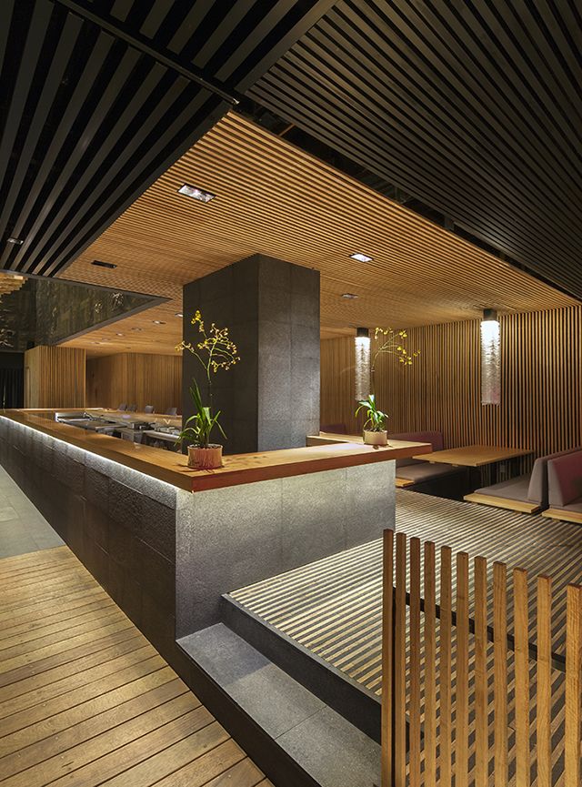 the interior of a restaurant with wood flooring and wooden benches on either side of the counter