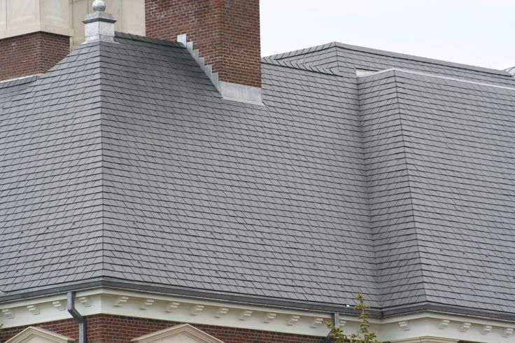 a clock on the side of a brick building with a steeple in the background