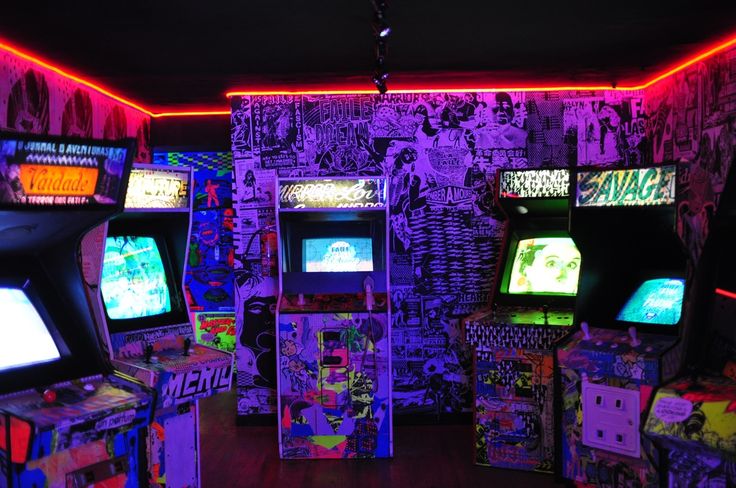 several video game machines are lit up with neon colors