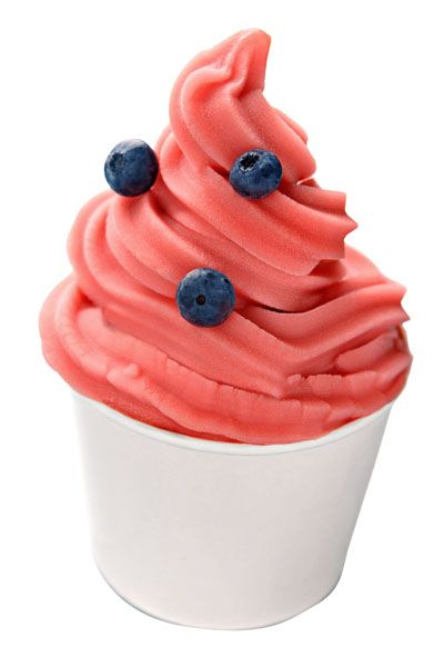 a cupcake with pink frosting and blueberries on top, sitting in a white container