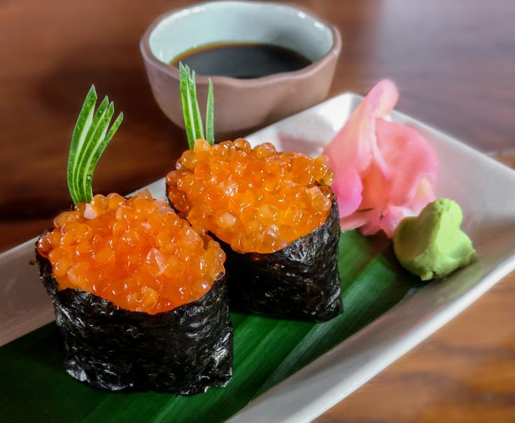 two pieces of sushi on a plate with dipping sauce