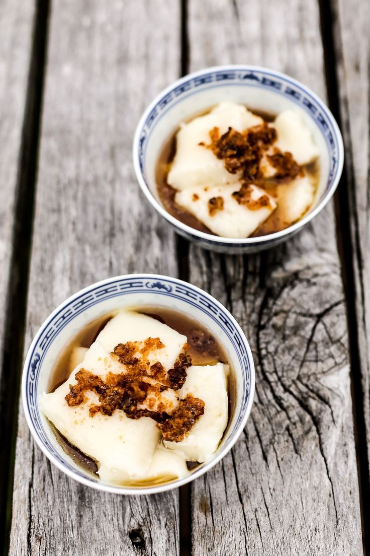 two bowls filled with food sitting on top of a wooden table next to each other