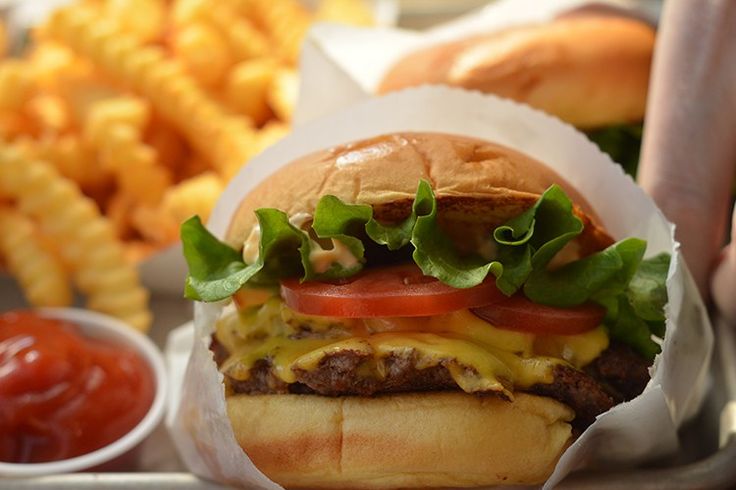 a cheeseburger with lettuce, tomato and onion on it next to french fries