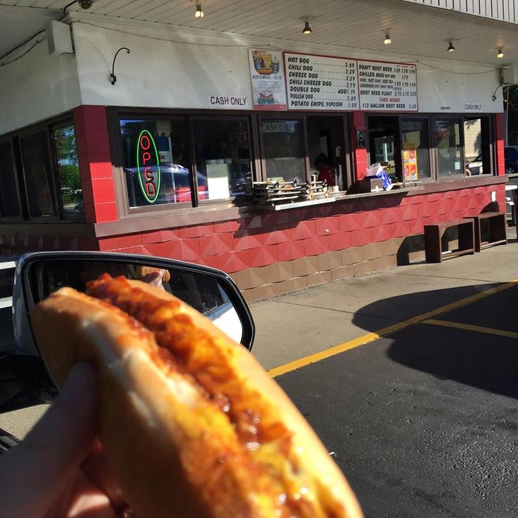 a person holding up a piece of food in front of a restaurant on the street