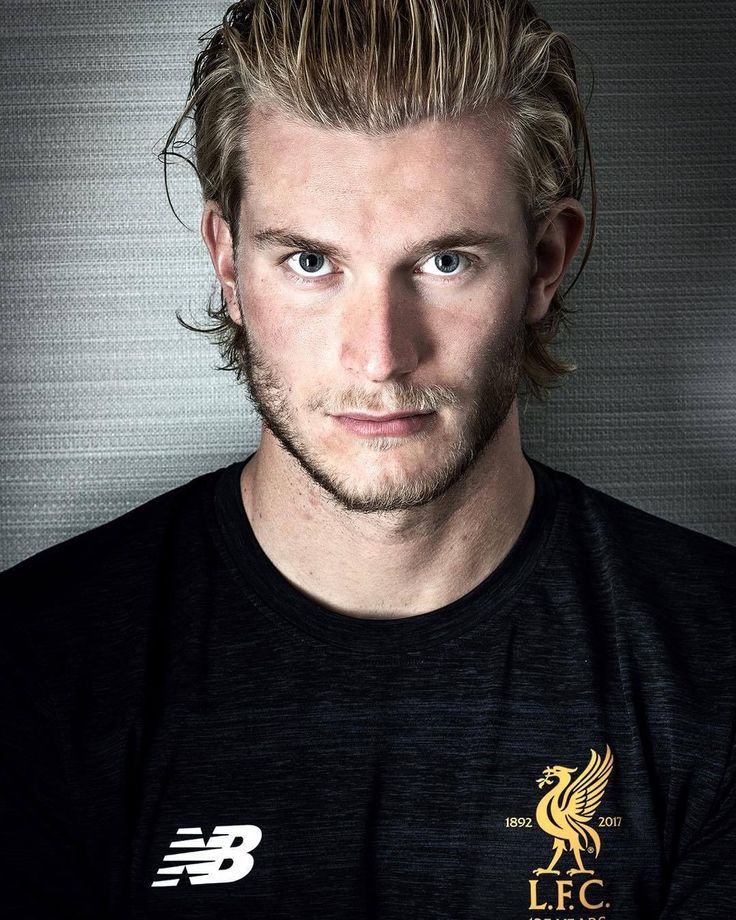 a man with blonde hair and blue eyes wearing a black t - shirt is looking at the camera