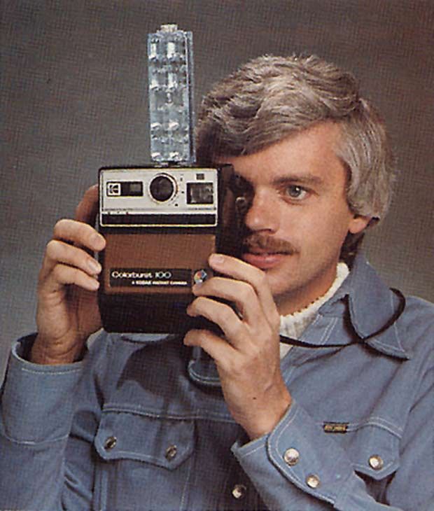 a man holding up an old fashioned camera