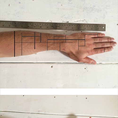 a person's hand with a ruler on their arm and the other hand holding a piece of metal