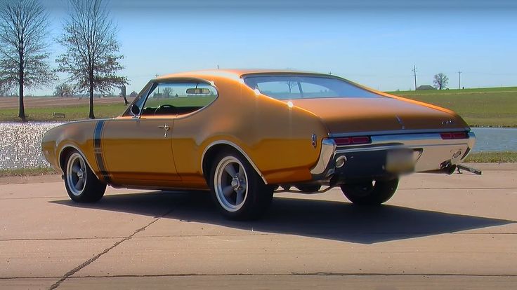 an orange muscle car is parked on the pavement