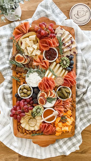 a wooden platter filled with lots of different types of cheeses and crackers