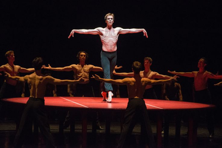 a man standing on top of a stage surrounded by dancers