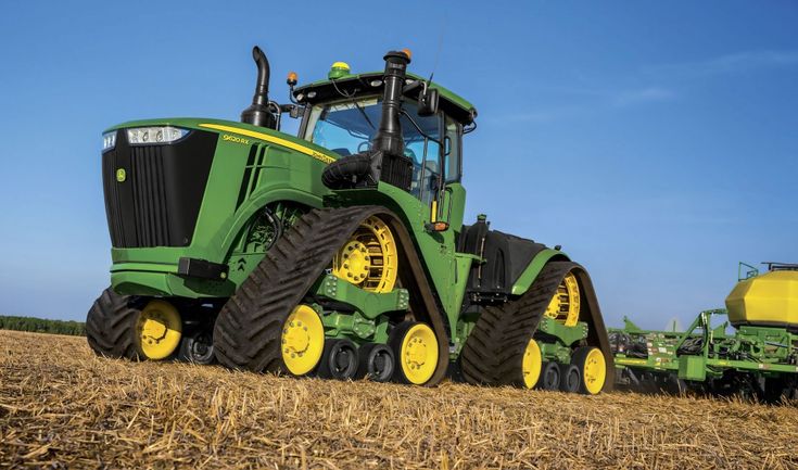 a large green tractor driving through a field