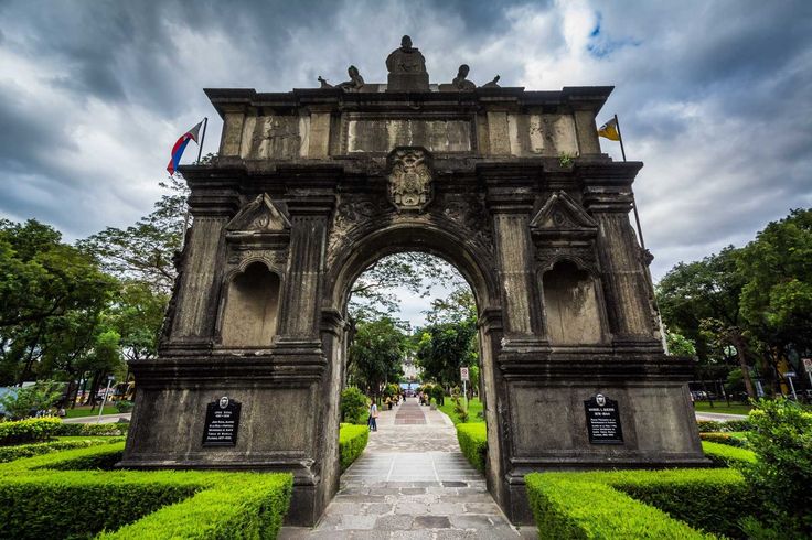 an arch in the middle of a lush green park