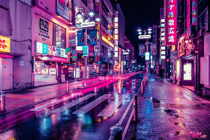 a city street filled with lots of neon signs and traffic lights at night in the rain