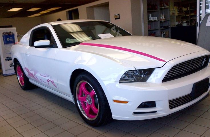 a white car with pink stripes parked in a showroom