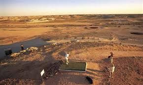 two men playing frisbee golf in the middle of an empty desert plain at sunset