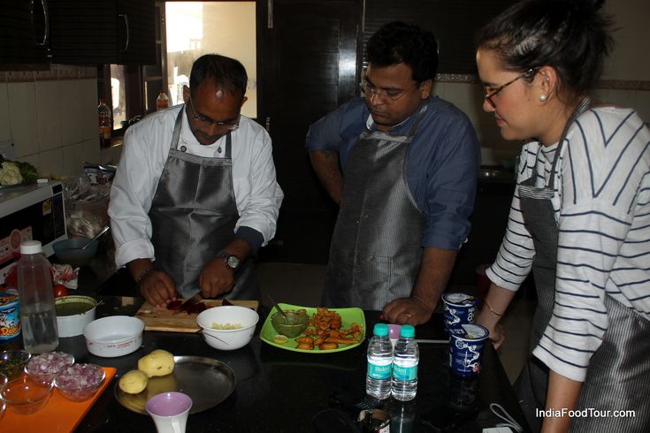 three people standing in a kitchen preparing food