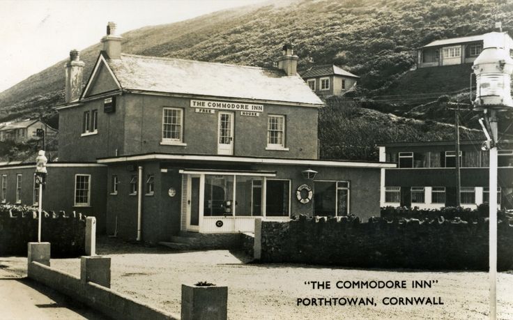 an old black and white photo of a building in the middle of town with mountains in the background