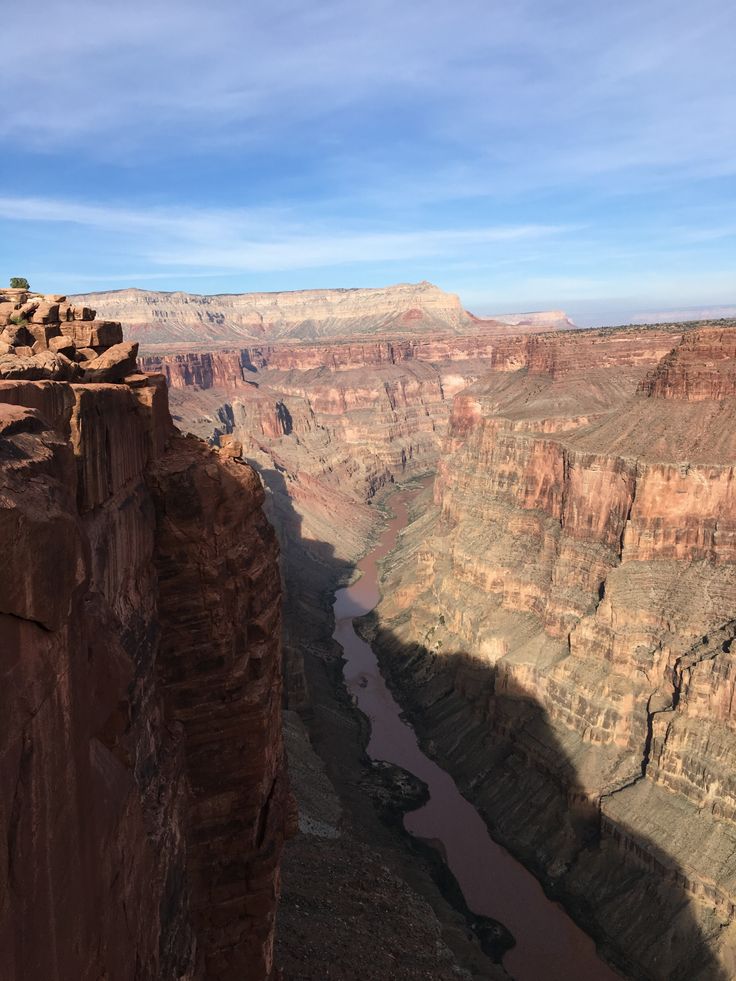 a man standing on the edge of a cliff overlooking a river and canyon below him