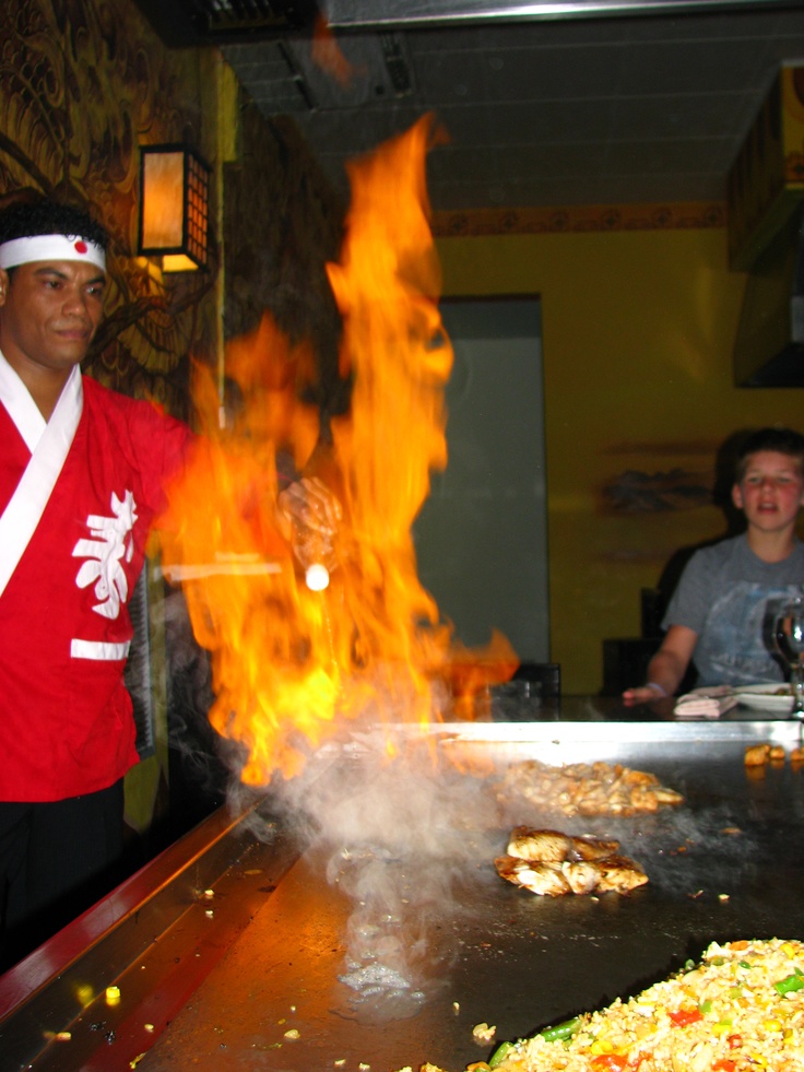 a man standing in front of a grill with flames coming out of it