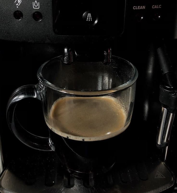 a glass cup filled with liquid sitting on top of a coffee maker's burner