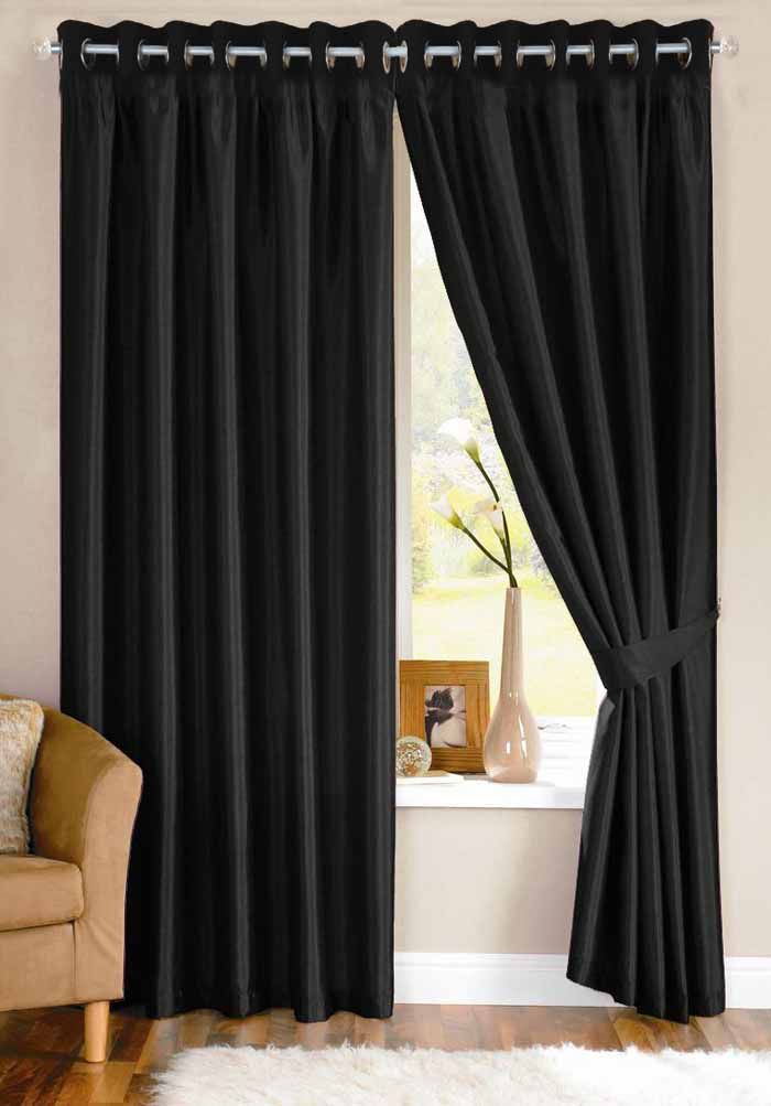 a living room with black curtains and a chair