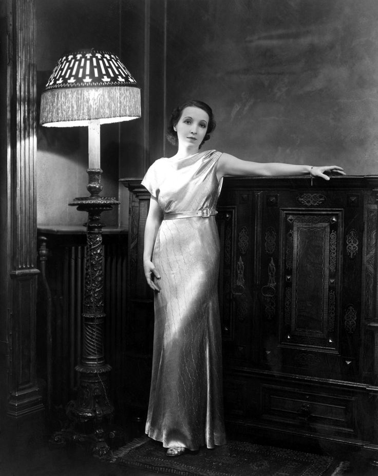 an old photo of a woman standing next to a lamp