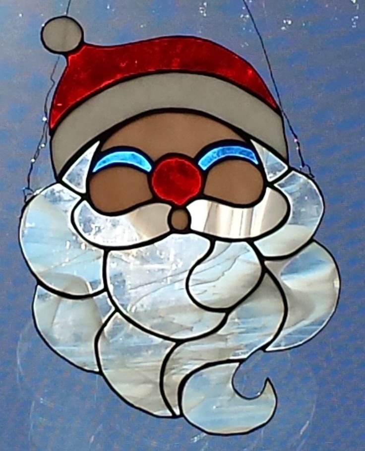 a stained glass santa clause ornament hanging from a hook on a blue background