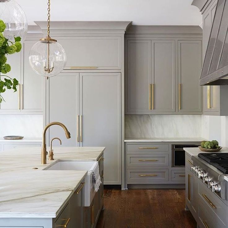 a kitchen with gray cabinets and marble counter tops