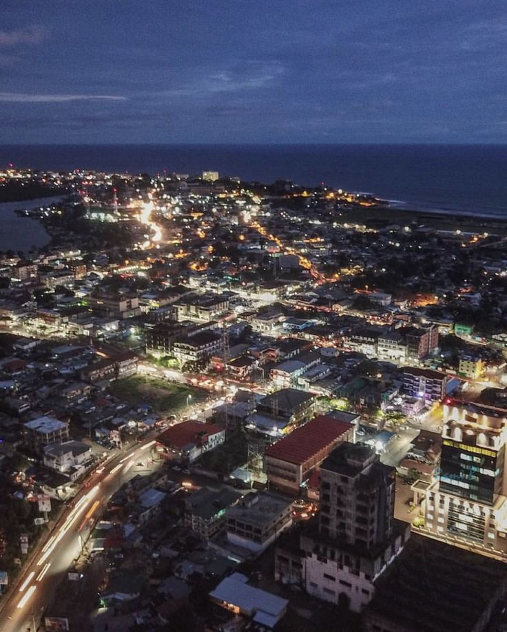 an aerial view of a city at night with the ocean in the backgroud