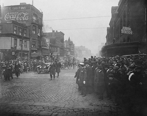 an old black and white photo of people in the street