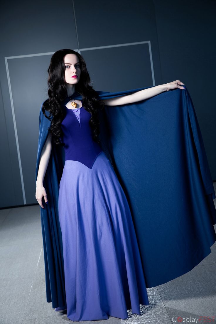 a woman in a blue and purple dress is holding a cape image.