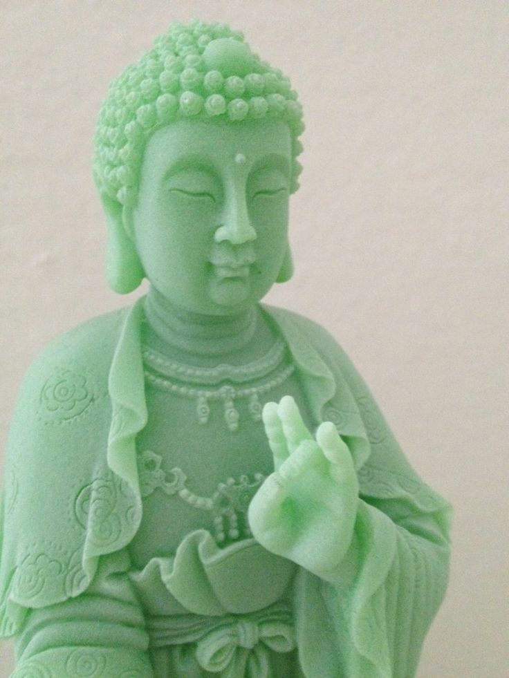 a green buddha statue sitting on top of a table