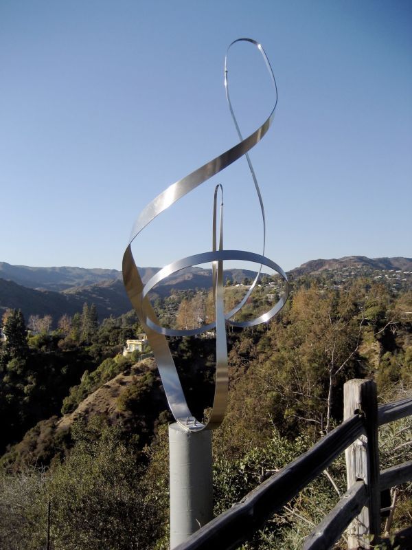 a metal sculpture on the side of a hill with trees and hills in the background