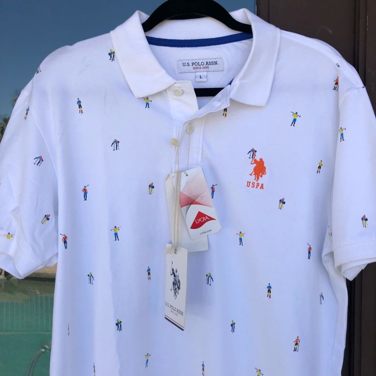 U.S. Polo Assn Polo White With Allover Colorful Polo-Playing People Orange Uspa Embroidered Logo On Chest 2-Button Placket, White Buttons (Extra Included) White Knit Collar And Cuffs Men's Size Large (L) (Check Measurements) Chest (Pit To Pit) 22 Inches Length 30 Inches New With Tags Uspa Polo Tshirt Men, Casual Printed Polo Collar Top, Printed Cotton Polo Collar Top, White Collared Printed T-shirt, White Printed Collared T-shirt, Printed Cotton Tops With Polo Collar, Casual Polo Collar Top With Graphic Print, White Casual Polo Collar Shirt, Casual White Polo Collar Top