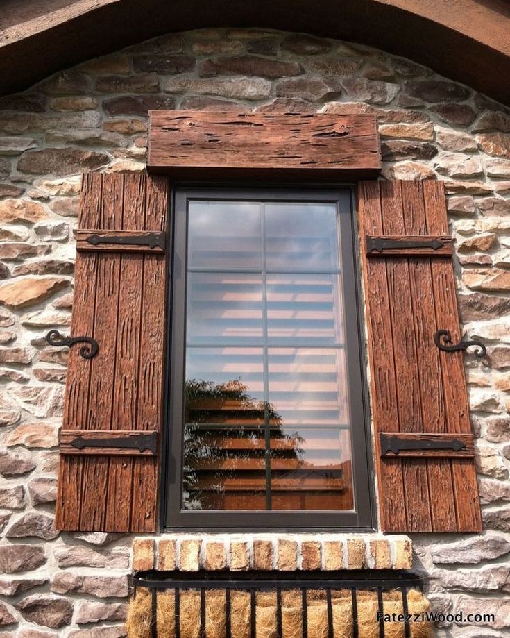 a window with wooden shutters on the side of a stone building