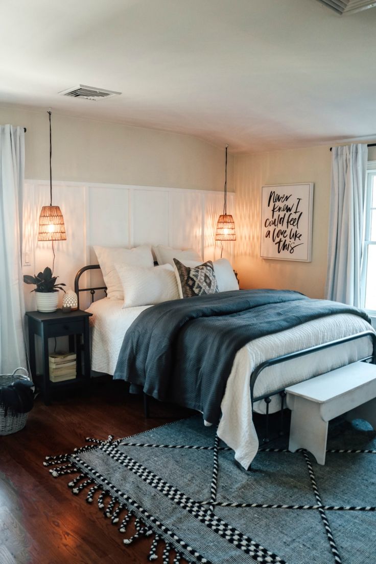 a bedroom with a large bed and black and white rugs on the hardwood floor