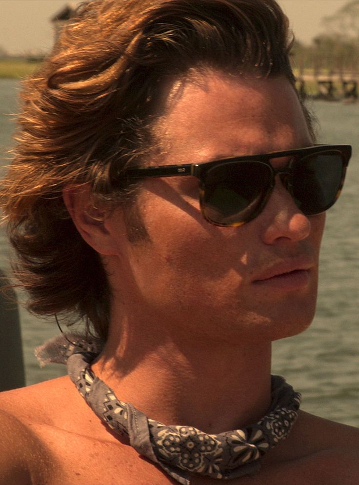 a shirtless man wearing sunglasses on a boat