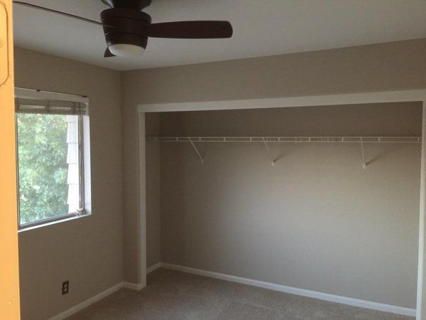 an empty room with a ceiling fan and window