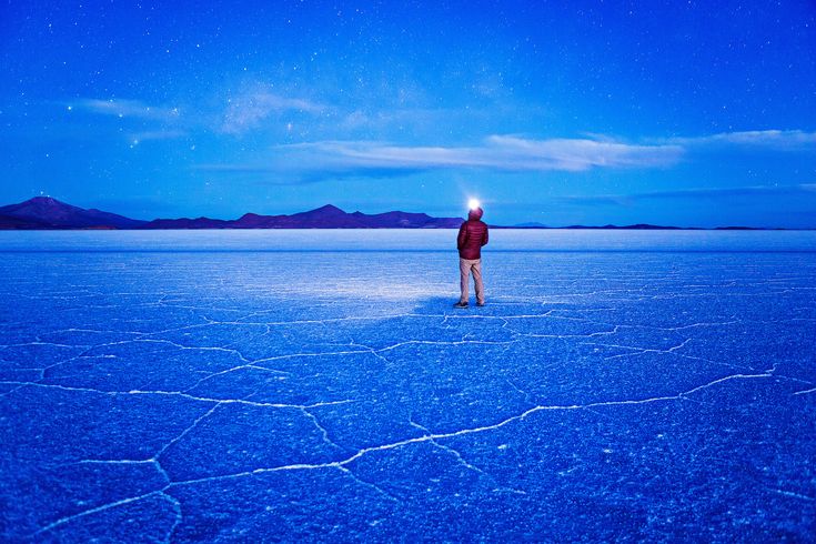 a man standing in the middle of a vast expanse of water under a blue sky