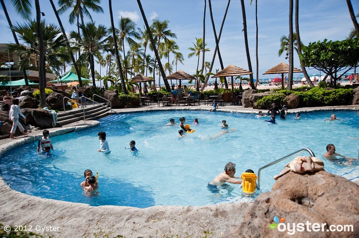 people are swimming in an outdoor pool surrounded by palm trees