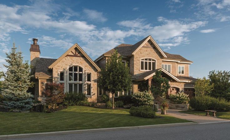 a large brick house sitting on the side of a road next to a lush green field