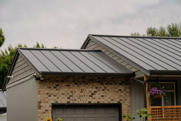 a brick house with a metal roof and two garage doors