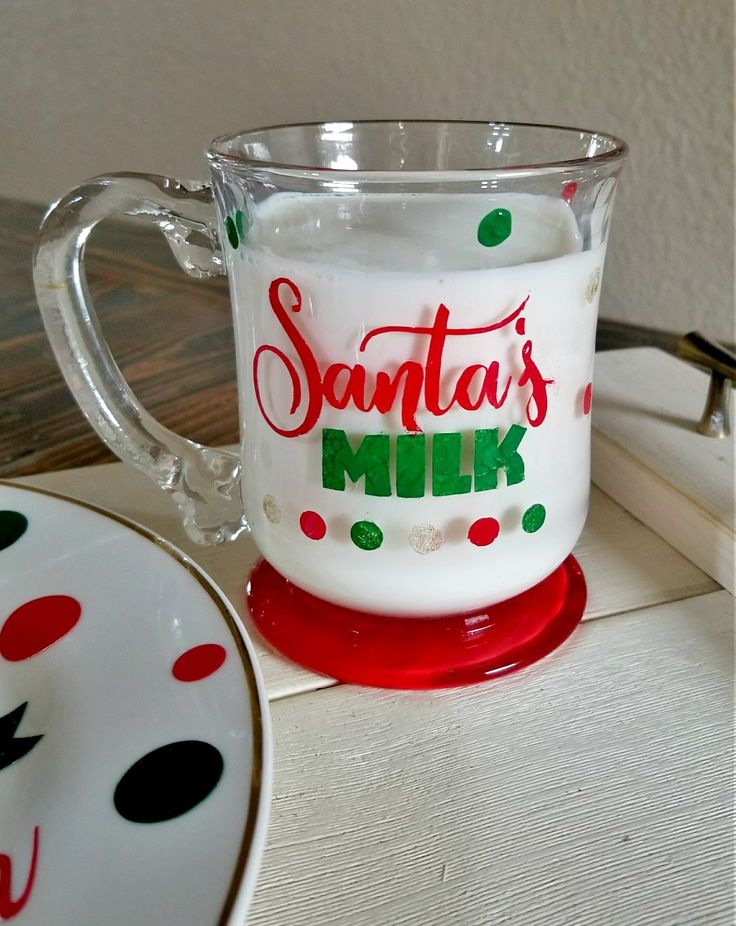 a santa's milk mug sitting on top of a table next to a plate