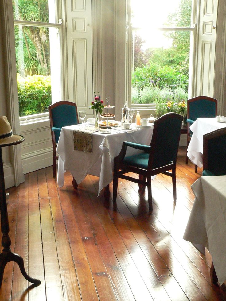 a dining room with wooden floors and white table cloths set for two people at the dinner table