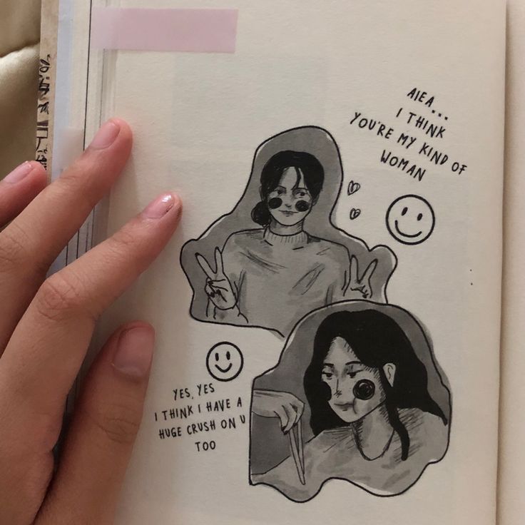 an open book with some drawings on the pages and someone's hand holding it